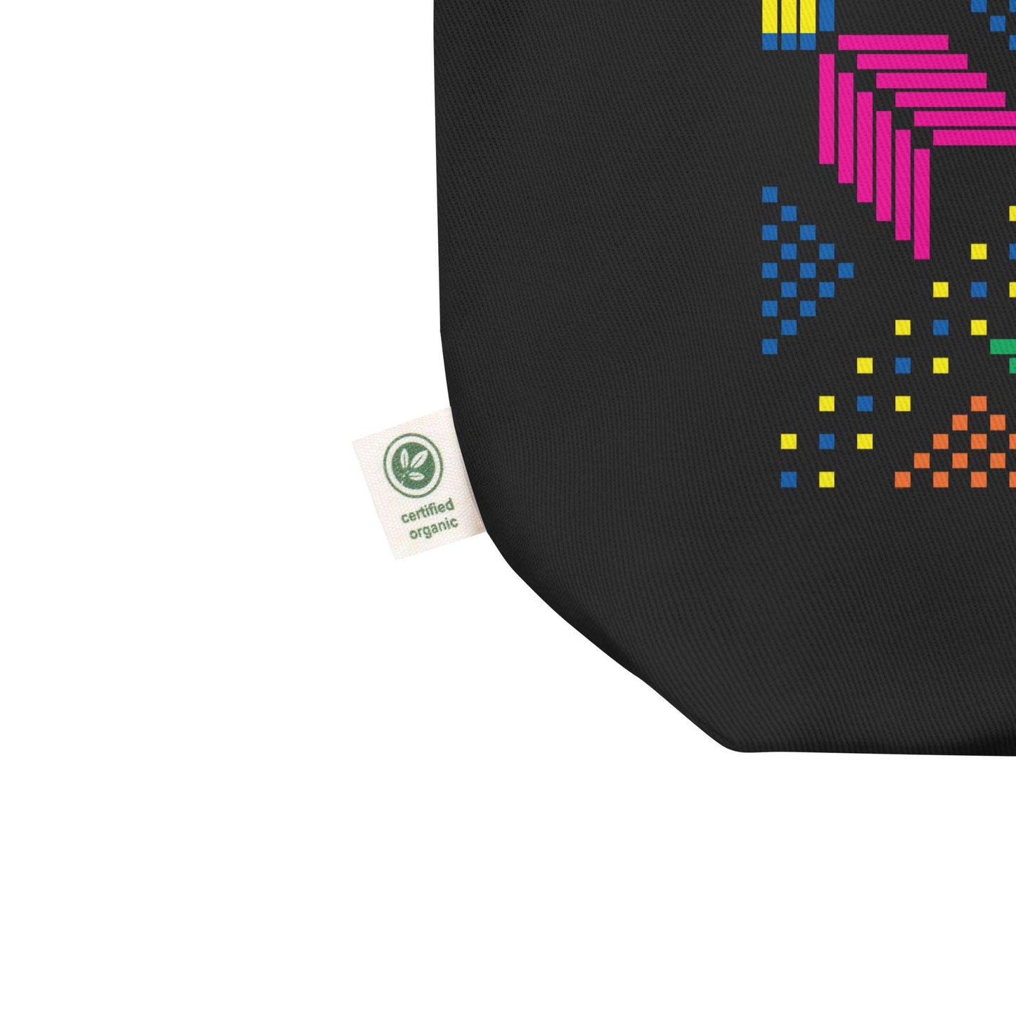 Detail of the tag on a 100% organic cotton black eco tote bag with a colorful pixelated design of flowers and dots. The tag says "certified organic".