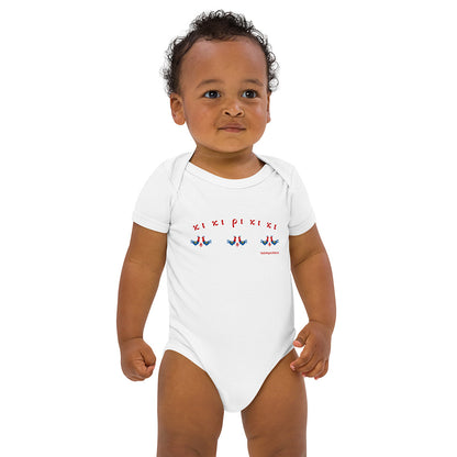 A standing baby wearing a short-sleeved white baby bodysuit made of 100% organic cotton. On the front is a repeating design of red and blue roosters with the Greek words "κι κι ρι κι κι" above them.