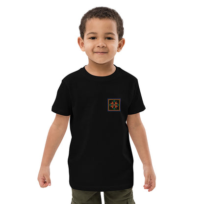 A close-up of a boy wearing a black organic cotton t-shirt with an orange flower design embroidered on the top left. The flower is enclosed within three borders of yellow, pink, and blue.