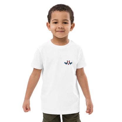 A boy wearing a white t-shirt made of 100% organic cotton with a pair of red and blue roosters embroidered on the top left.