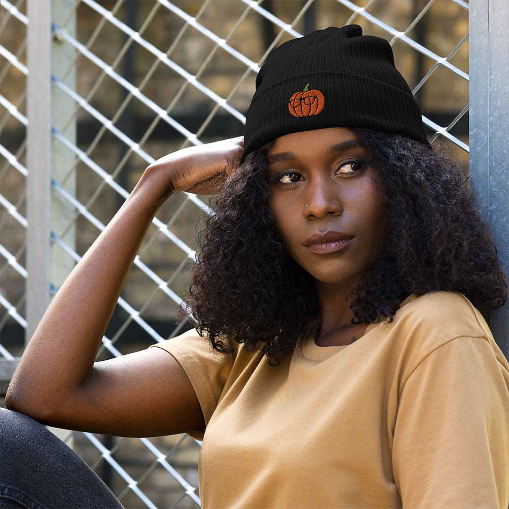 A woman wearing a spooky Halloween ribbed black beanie made of 100% organic cotton with a pumpkin embroidered on the front. The pumpkin is wearing glasses.