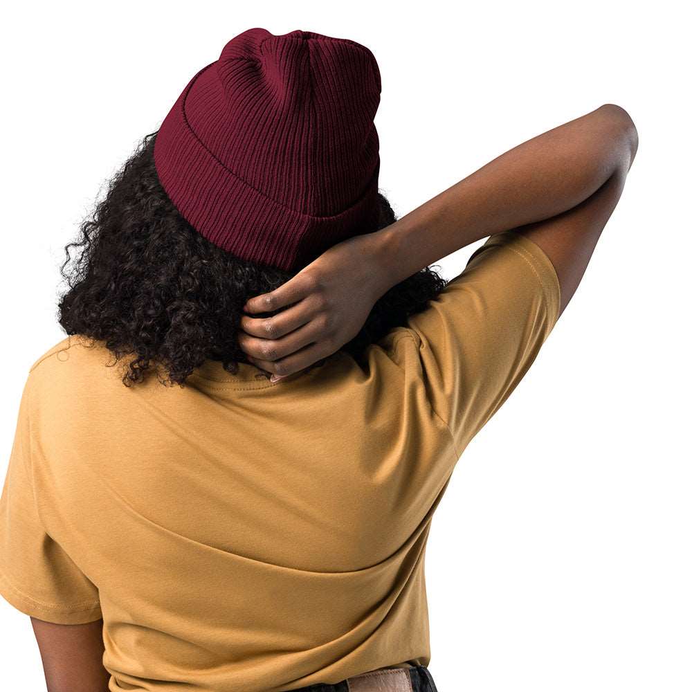 The back of a woman wearing a burgundy ribbed beanie made of 100% organic cotton.