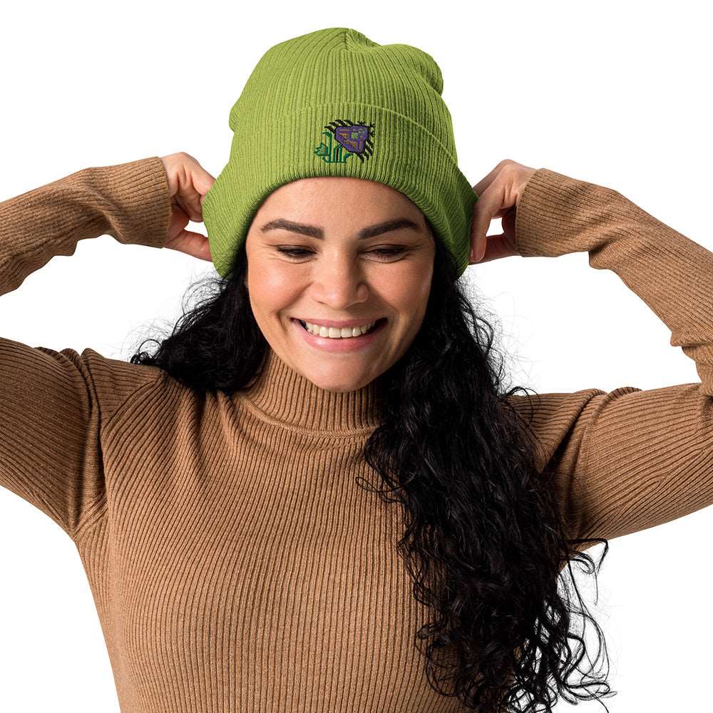 A woman wearing a light green ribbed beanie made of 100% organic cotton with an intricate purple flower embroidered on the front.