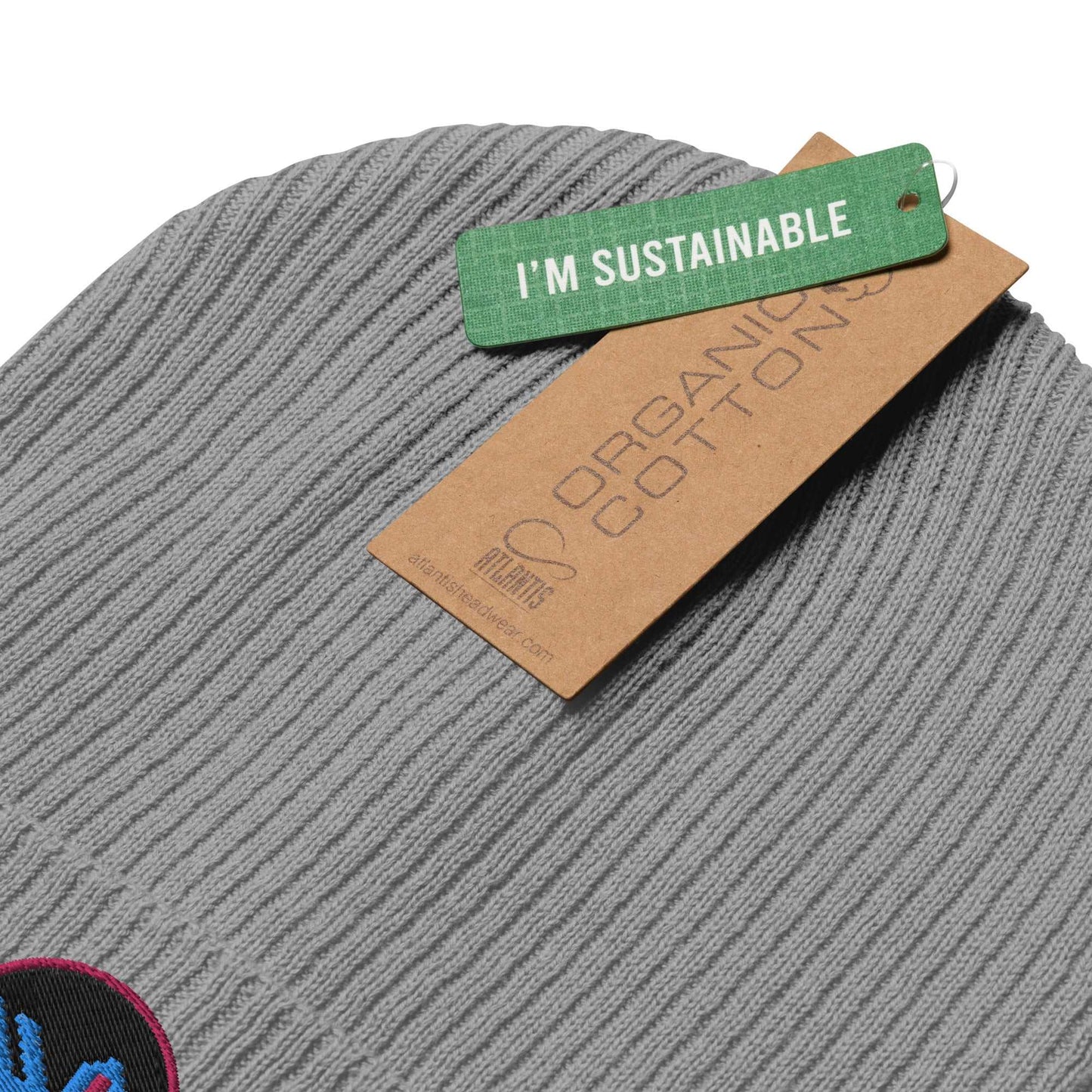 Detail of the tags on a grey beanie that say "I'm sustainable" and "organic cotton".