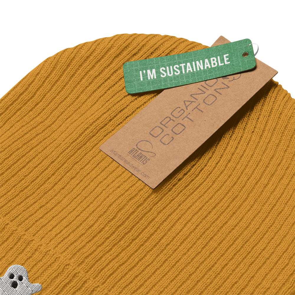 Detail of the tags on a mustard yellow beanie with a ghost embroidered on the front. The tags say "I'm sustainable" and "organic cotton".