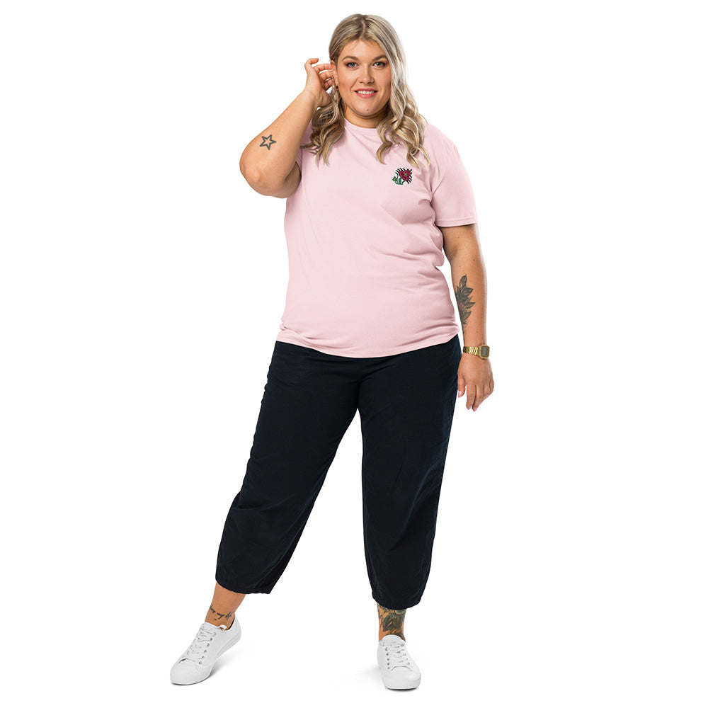 A woman wearing a light pink t-shirt made of 100% organic cotton with an intricate pink flower embroidered on the top left.