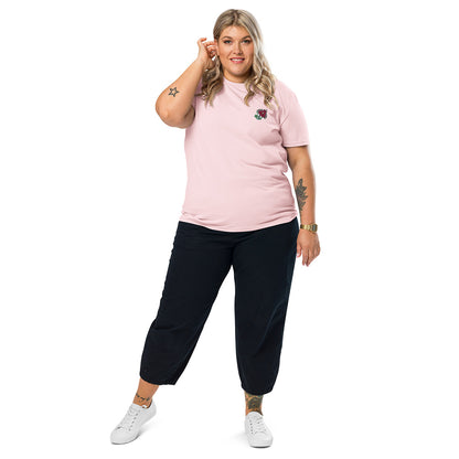 A woman wearing a light pink t-shirt made of 100% organic cotton with an intricate pink flower embroidered on the top left.