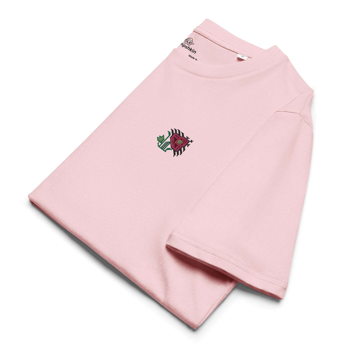 A light pink t-shirt made of 100% organic cotton with an intricate pink flower embroidered on the top left. The shirt is folded showing the embroidery detail and the left sleeve.