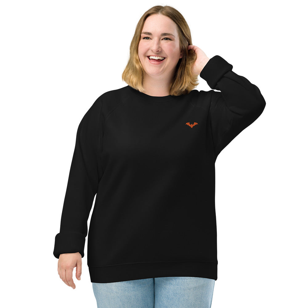 A woman wearing a black sweatshirt with a small orange bat embroidered on the top left.