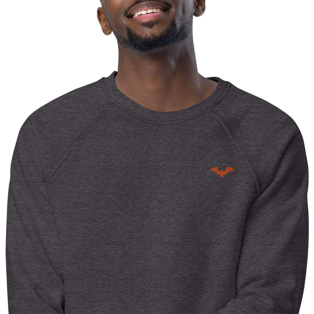 Closeup of a man wearing a spooky Halloween charcoal grey sweatshirt with a small orange bat embroidered on the top left.