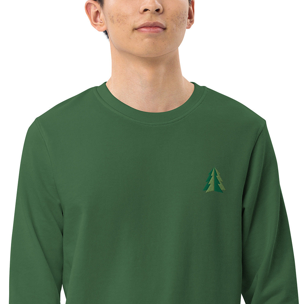 A closeup of a man wearing a festive green Christmas sweatshirt made of organic cotton and recycled polyester with a small minimalist two-tone pine tree embroidered on the top left.